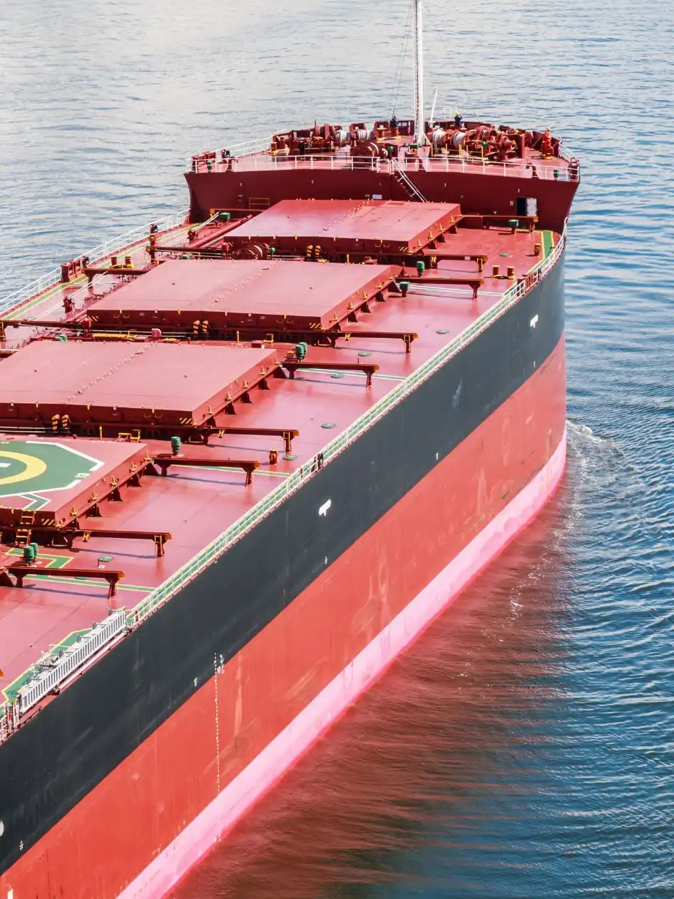 Aerial bow view of a large red-and-black bulk carrier underway on calm water