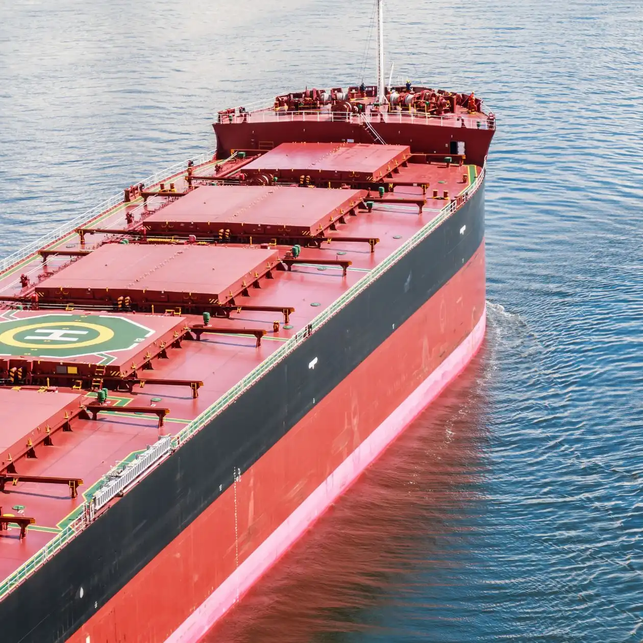 Aerial bow view of a large red-and-black bulk carrier underway on calm water