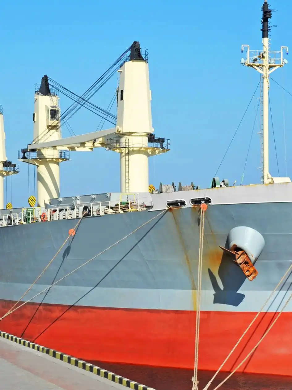 A geared bulk carrier with open hatches and deck cranes in port