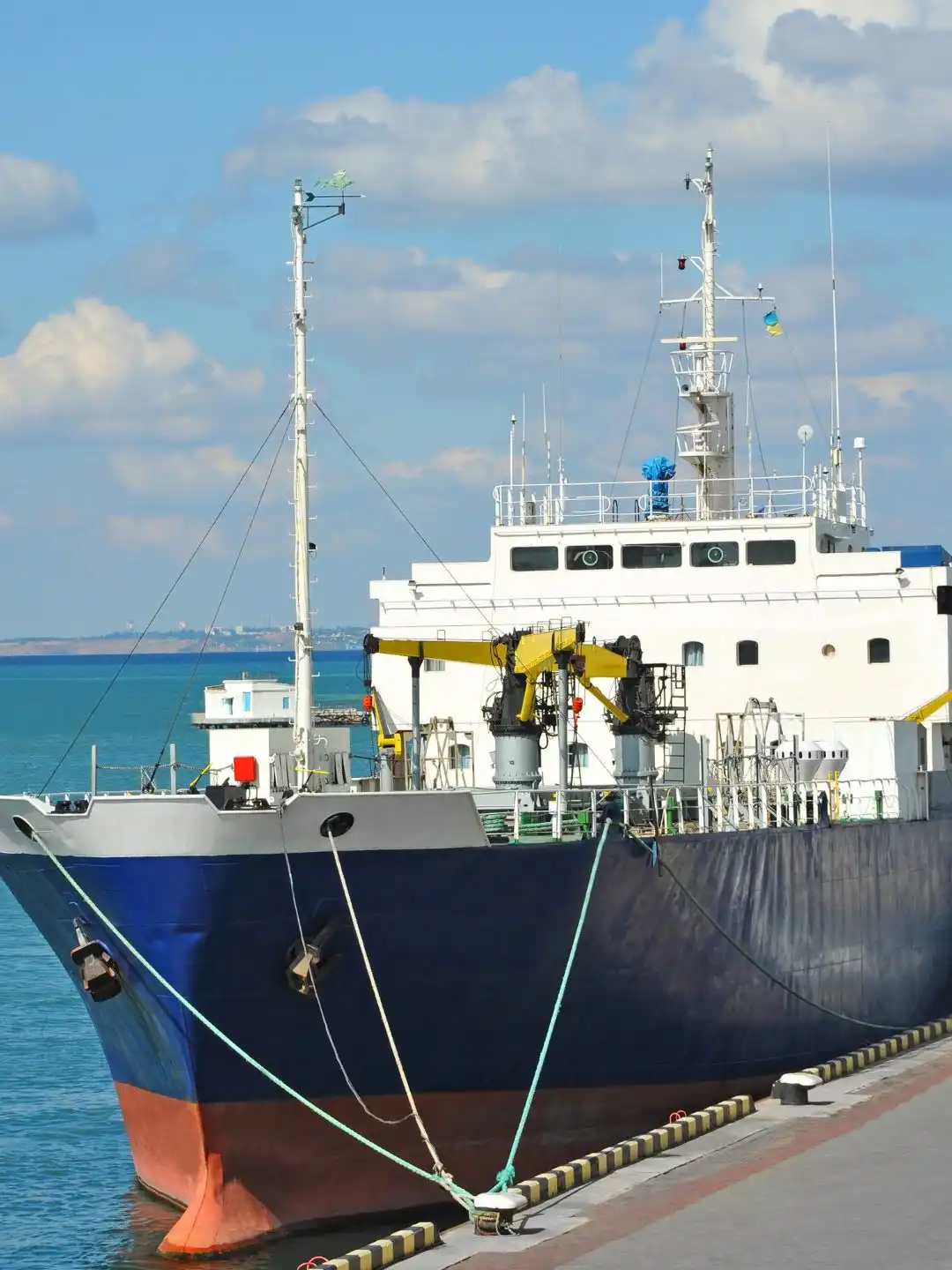 A large dark-hulled ore carrier moored at a deep-water pier