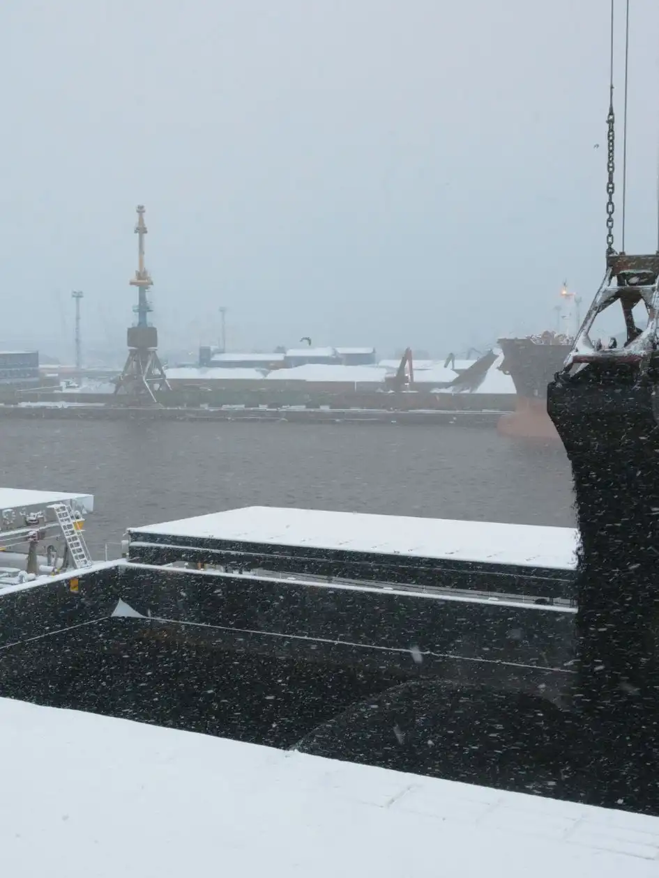 A mechanical grab depositing thermal coal into a bulk carrier's hold