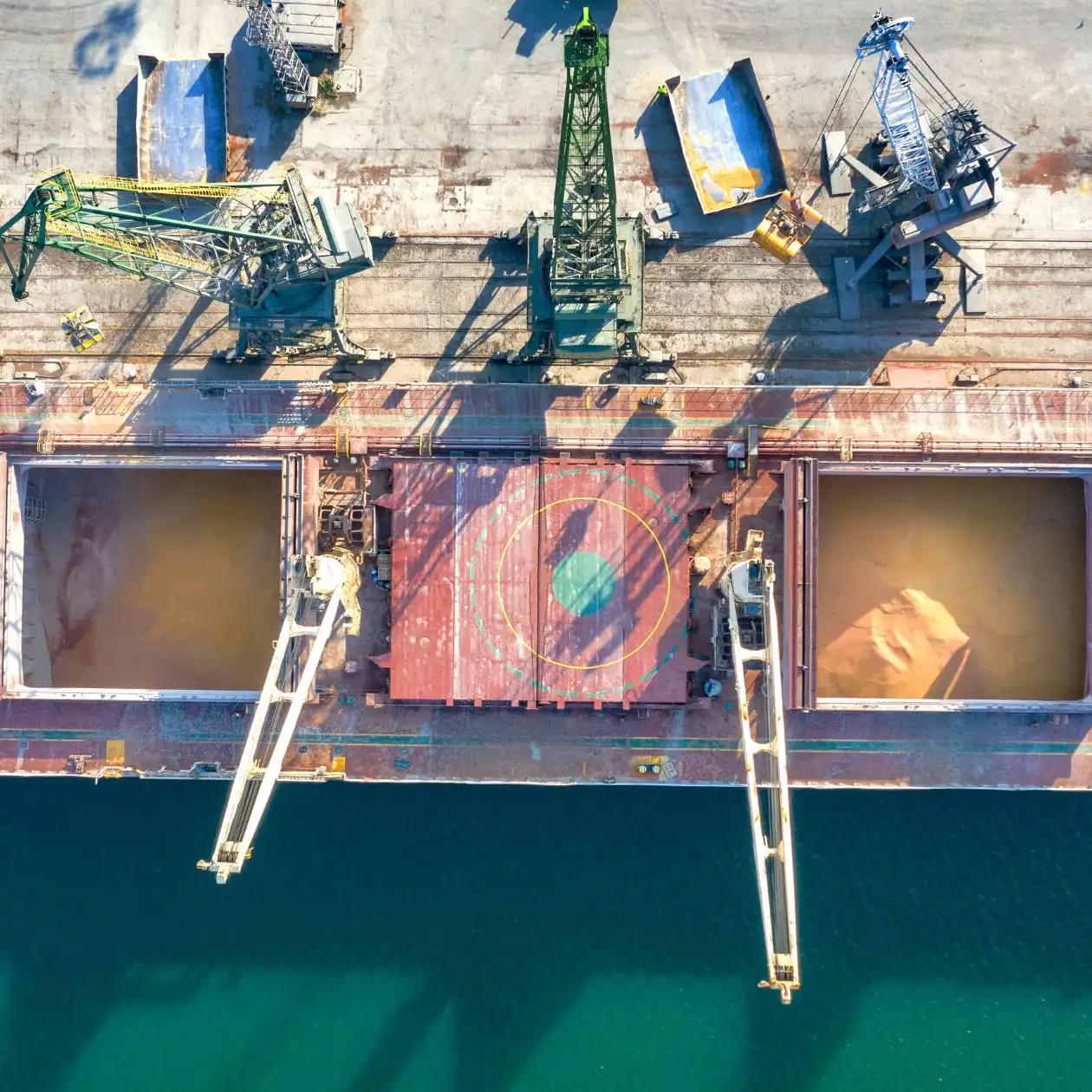 Aerial view of a docked bulk carrier with open hatches loading grain
