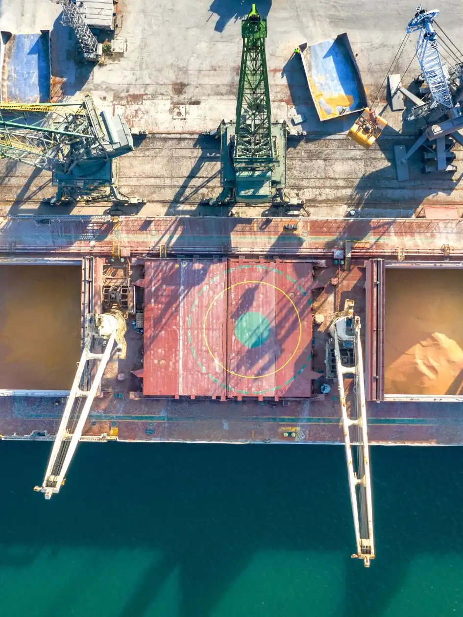 Aerial view of a docked bulk carrier with open hatches loading grain