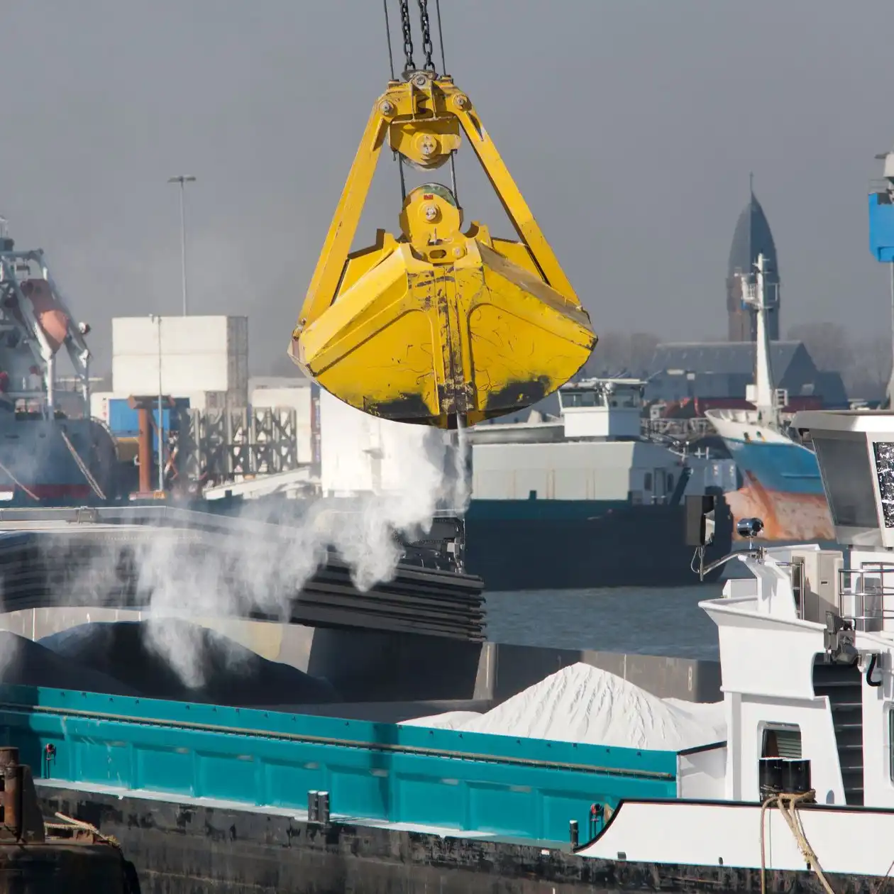 A ship at a port being loaded with powdered bulk material by a yellow crane