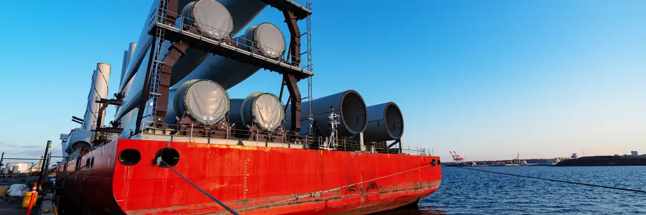 A ship loaded with large cylindrical project-cargo units moored at a harbour